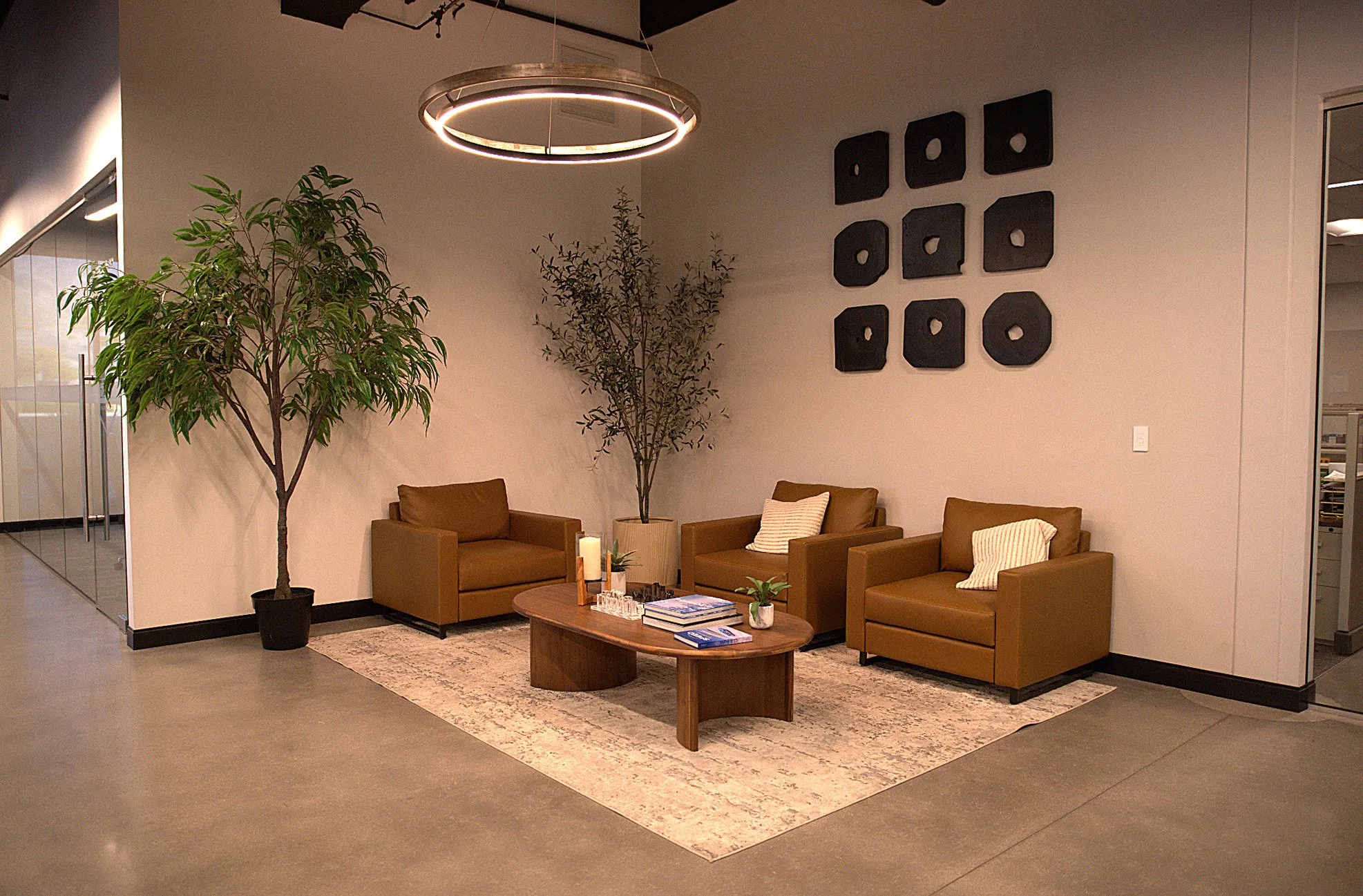 A quiet seating corner with a ring light, a potted tree and a row of framed prints