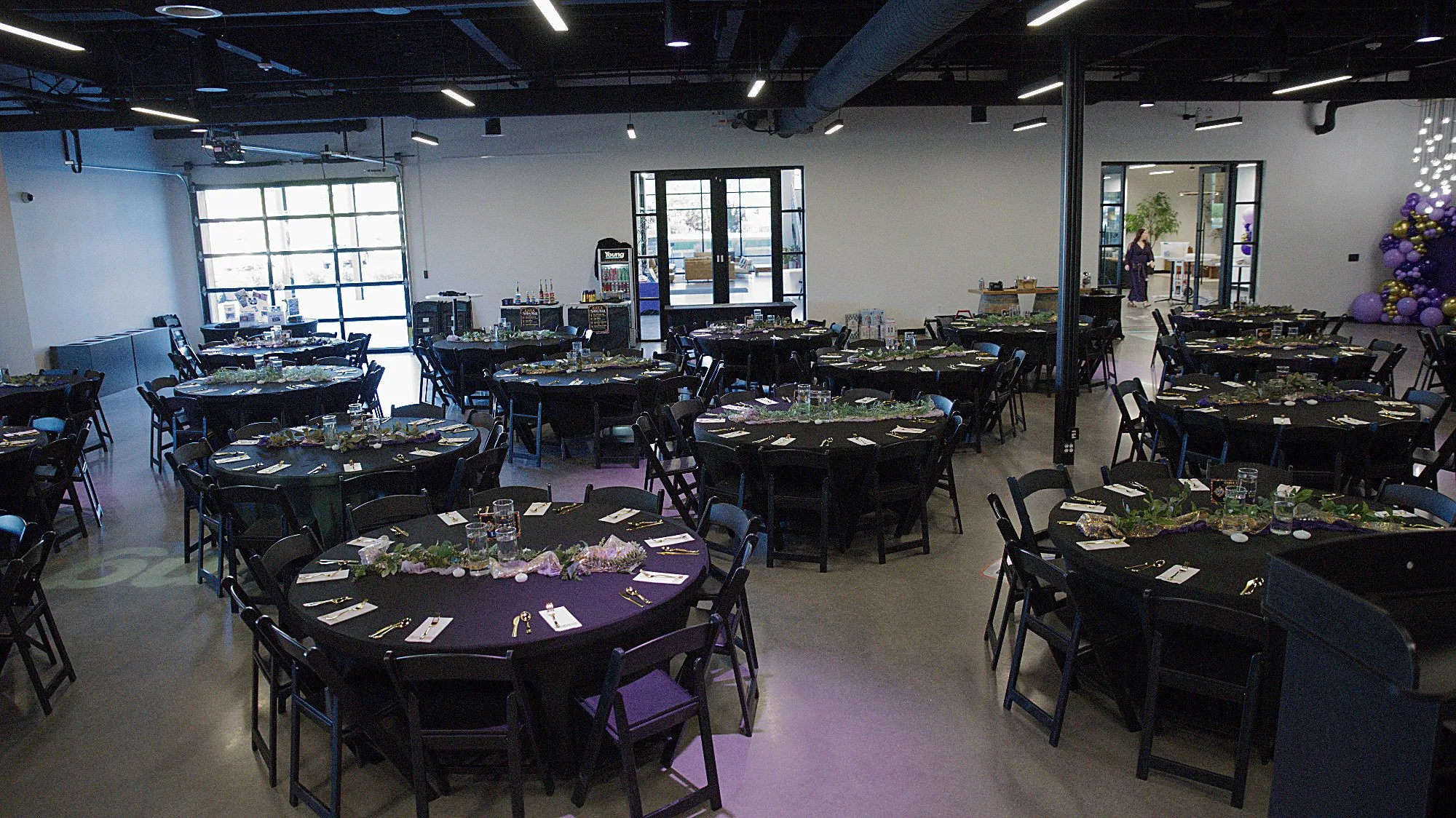 The empty dining room, round black tables set under a ceiling of track lights