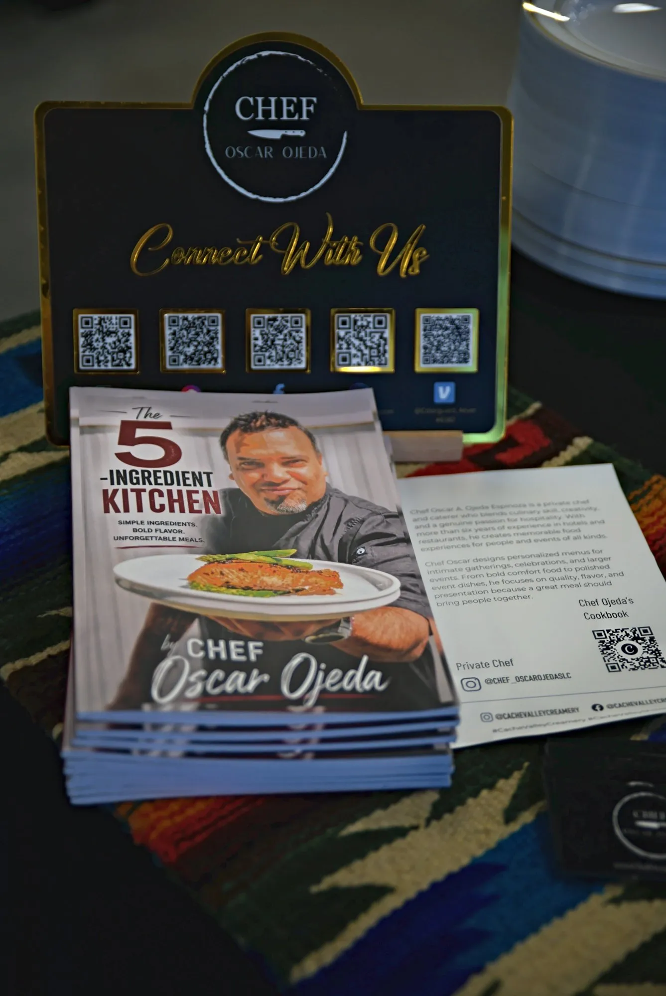 A stack of The 5-Ingredient Kitchen cookbooks under the chef's Connect With Us sign