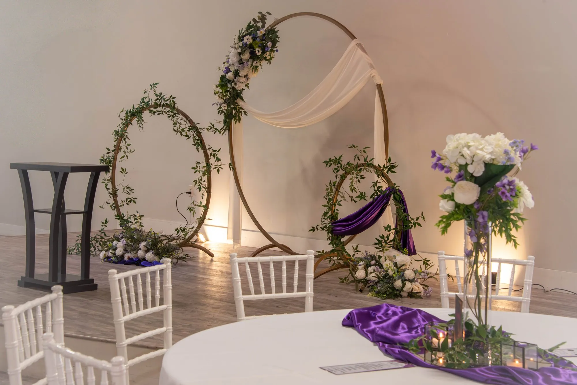 Gala stage set before doors open, with a floral arch, draped white fabric, and purple accents