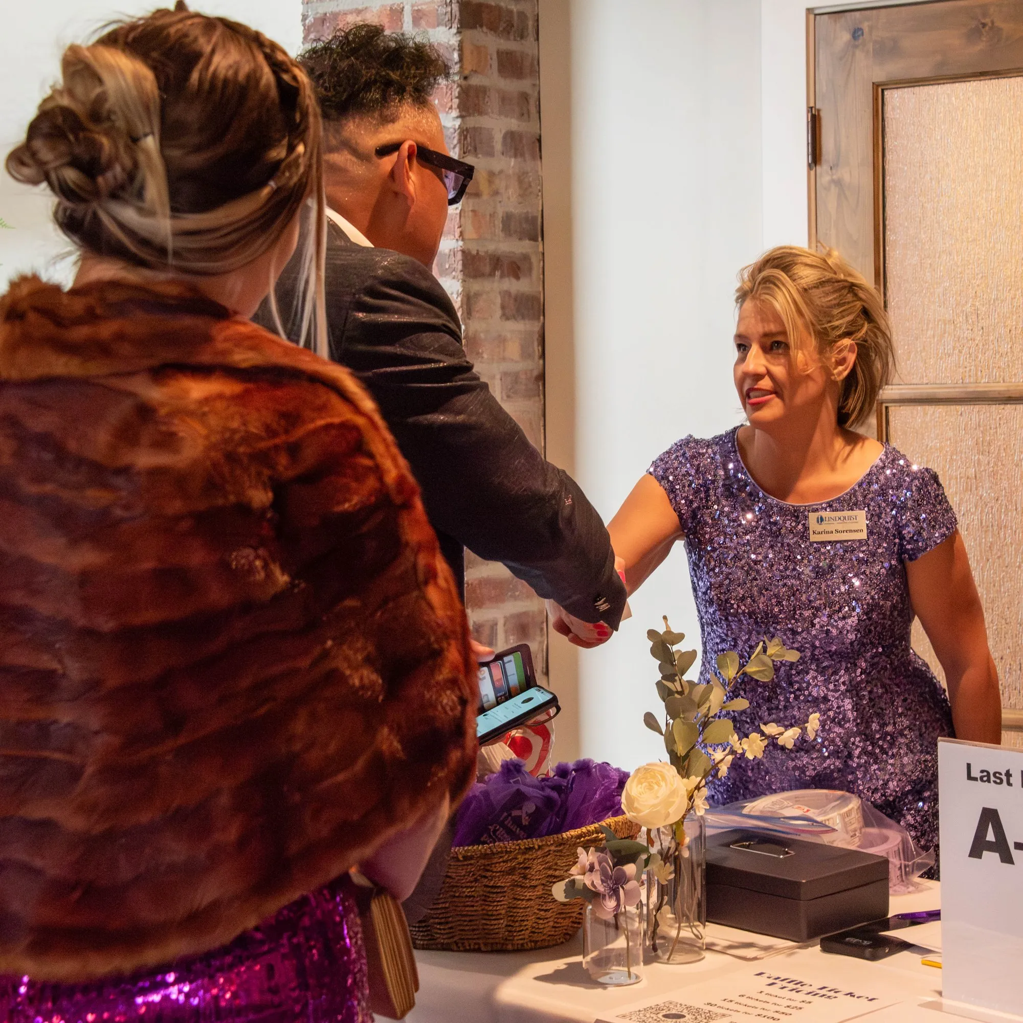 Volunteer greeting a guest at the gala check-in table