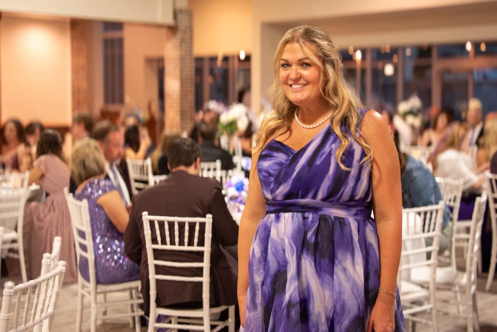 Guest in a purple gown standing in front of a full dining room