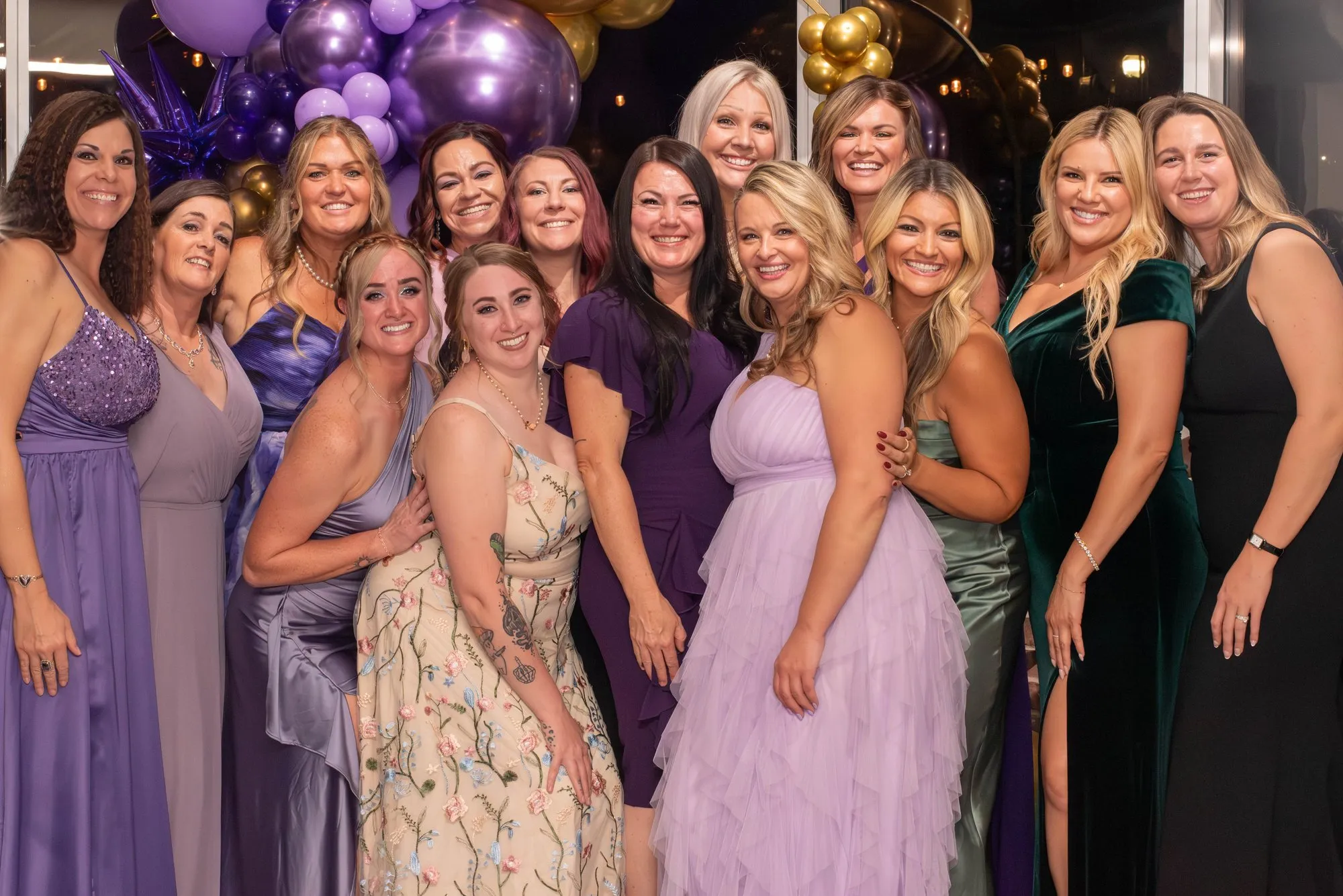 Group of friends in purple dresses posing together at the gala