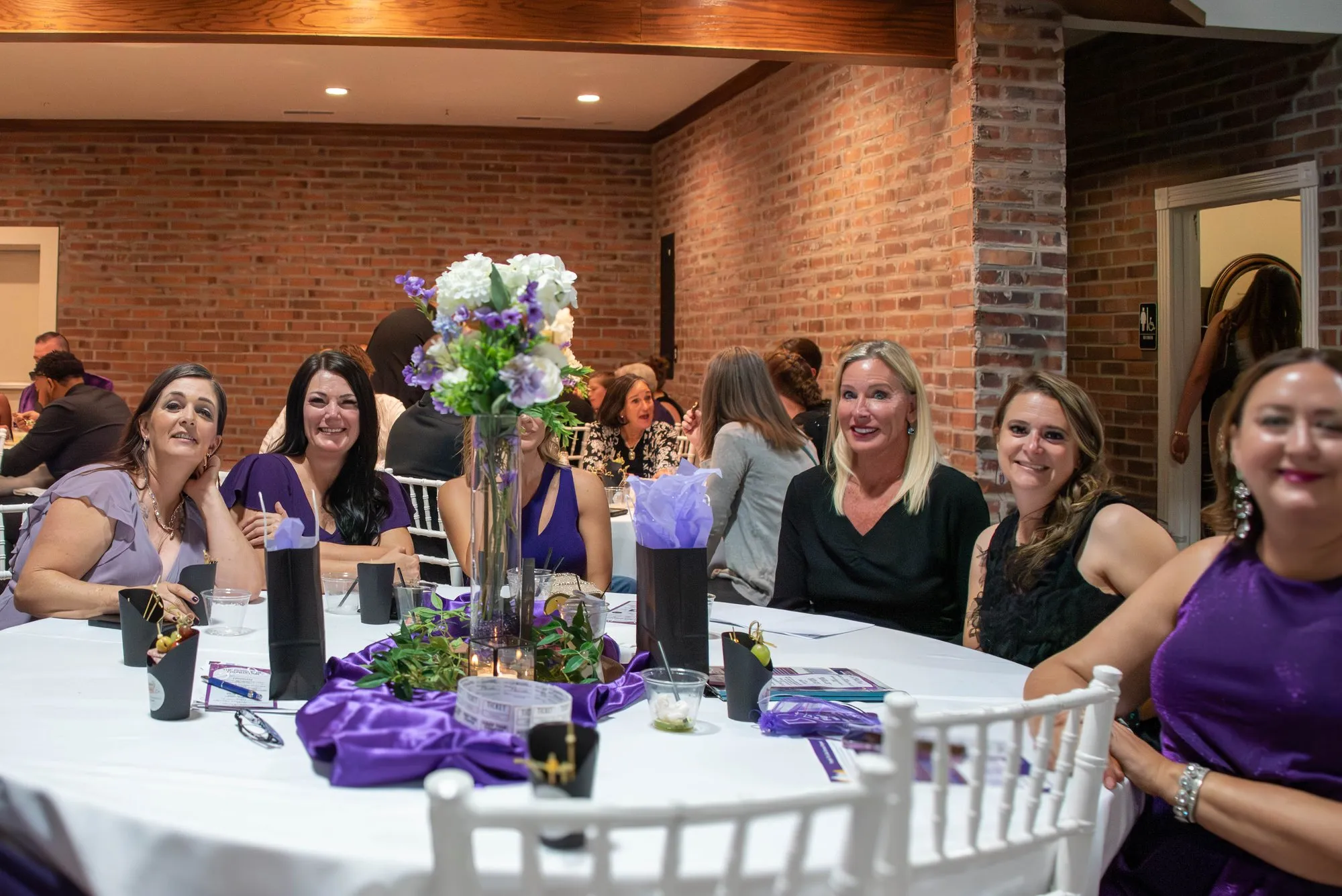 Table of guests smiling toward the camera during dinner