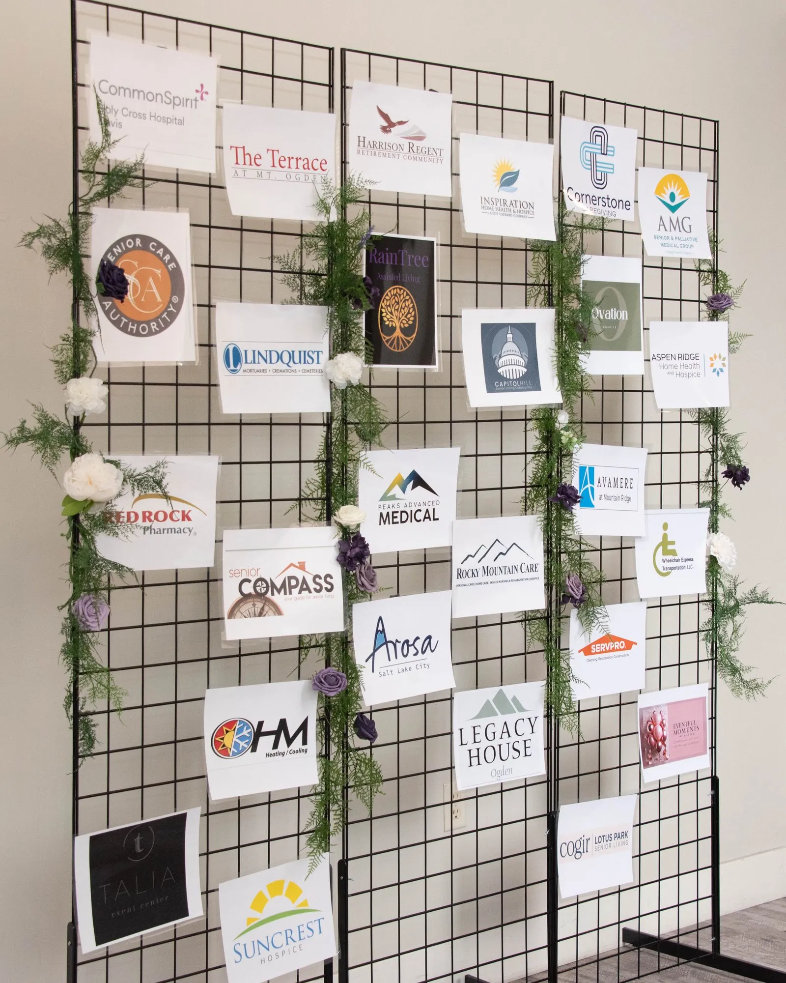 Sponsor logo board on a wire grid with greenery