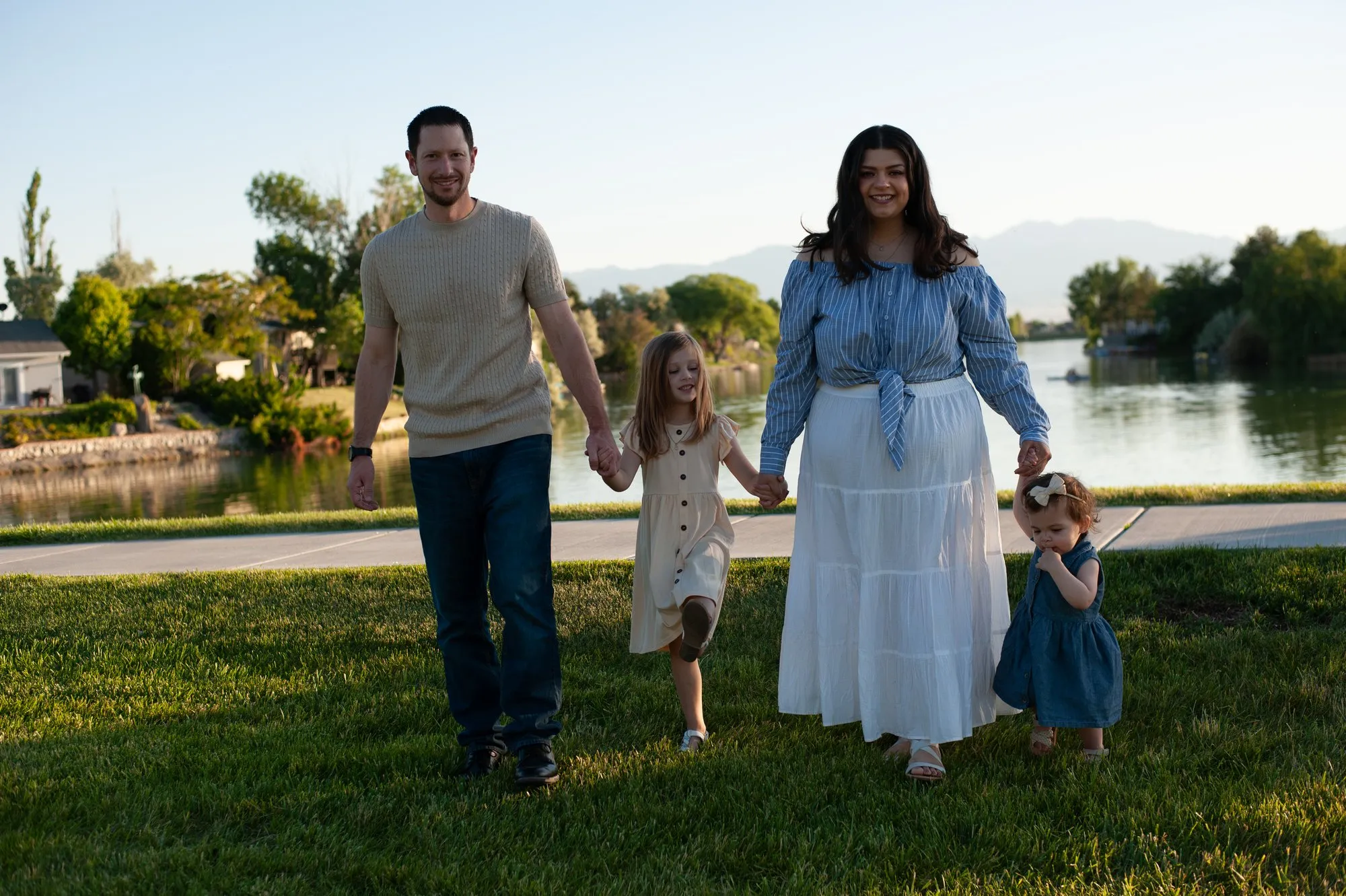 Family of four walking hand in hand across the park