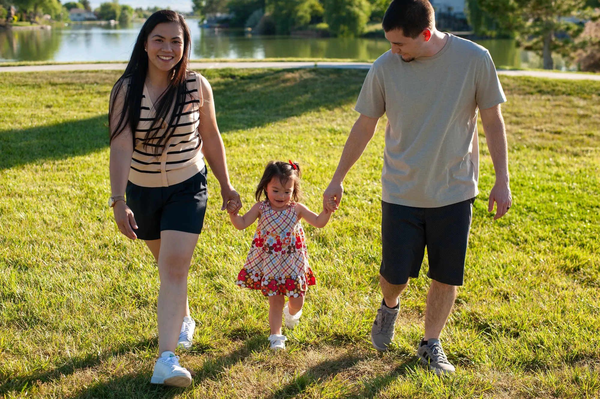 Parents swinging their toddler between them as they walk on the grass
