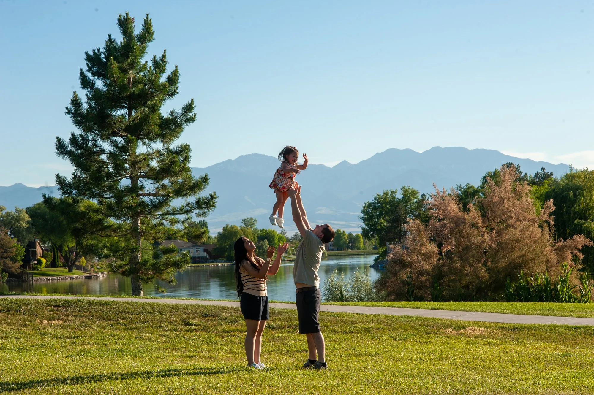 Father lifting his daughter overhead against a wide mountain view