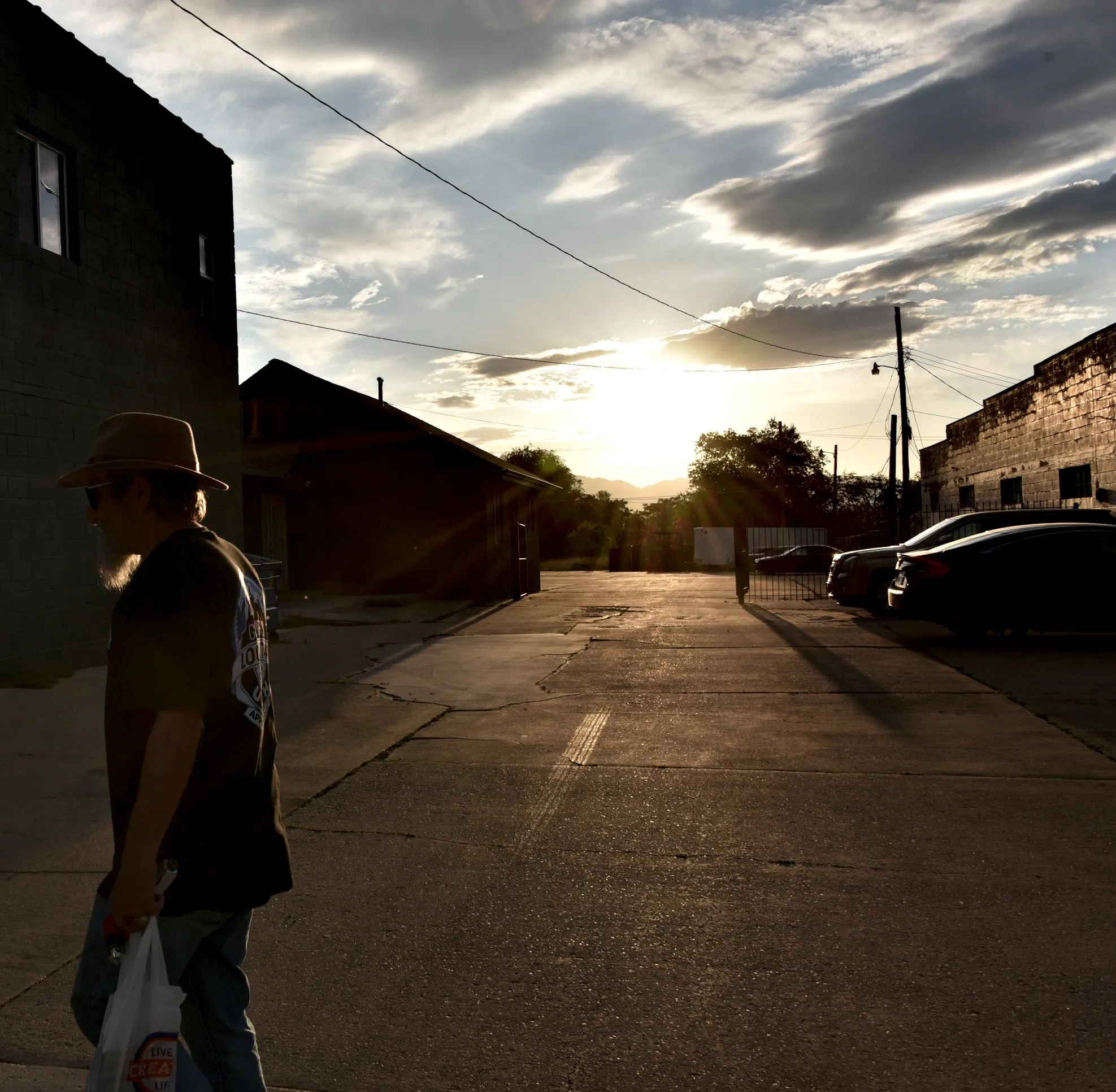 Silhouette of a man walking down a small-town street toward the sunset